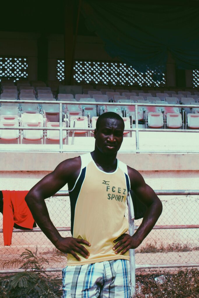 Strong athletic man posing confidently in an outdoor stadium.